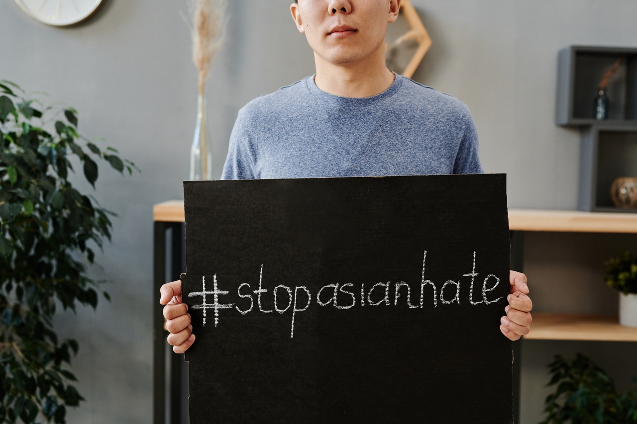 An Asian person holds a sign that says #stopasianhate (Hashtag Stop Asian Hate)